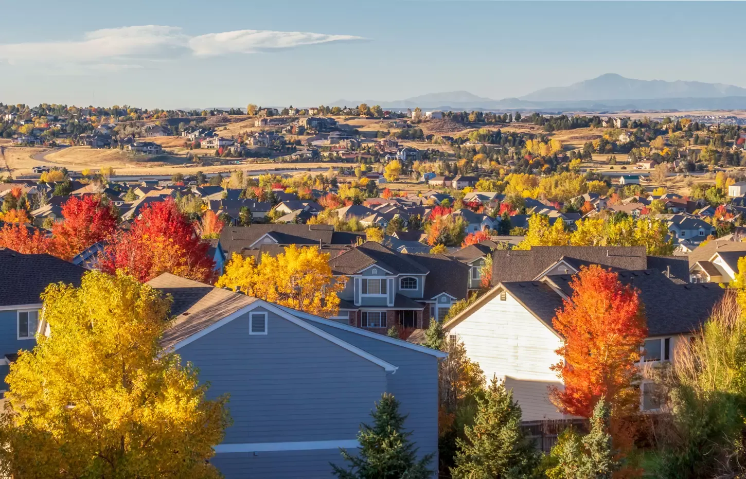 Autumn colors across a Colorado neighborhood with the Rocky Mountains beyond
