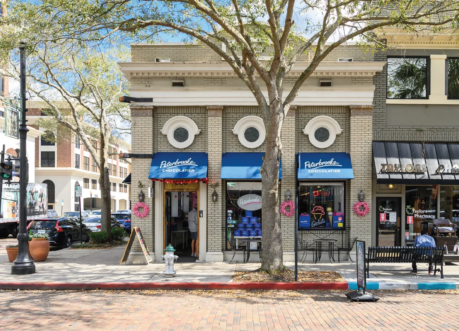 Historic brick commercial storefronts lining a tree-lined downtown street
