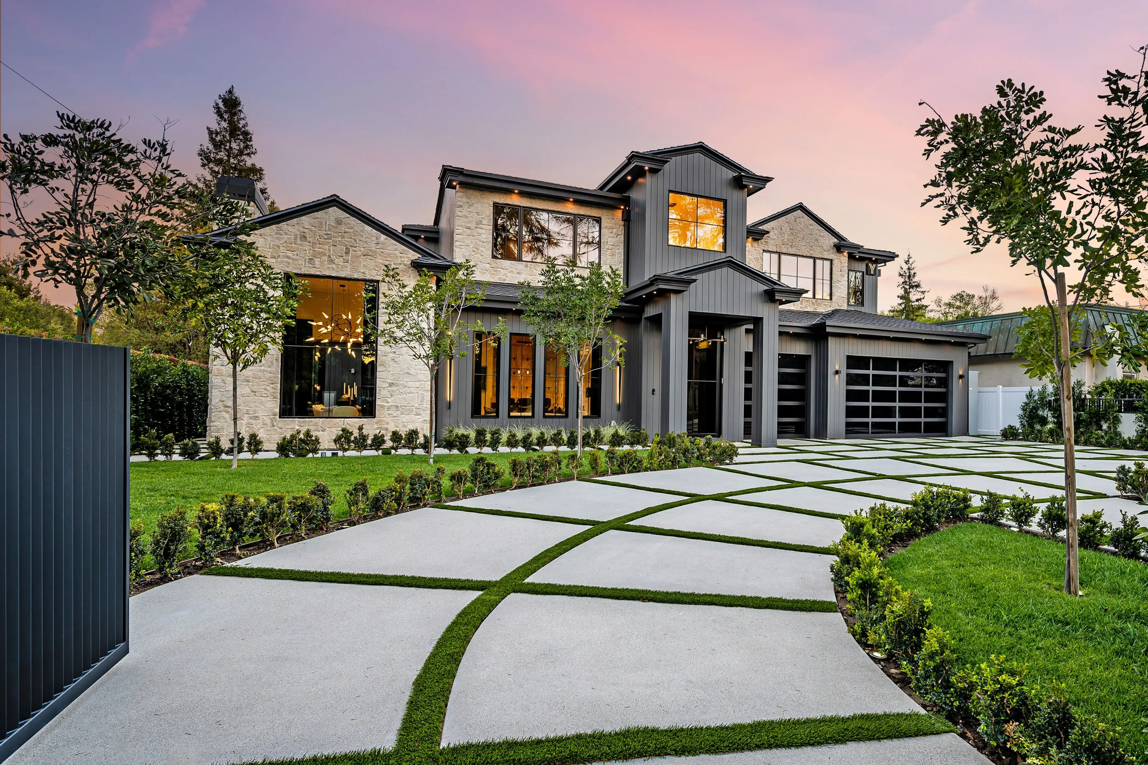 A modern farmhouse-style home glowing warmly at sunset