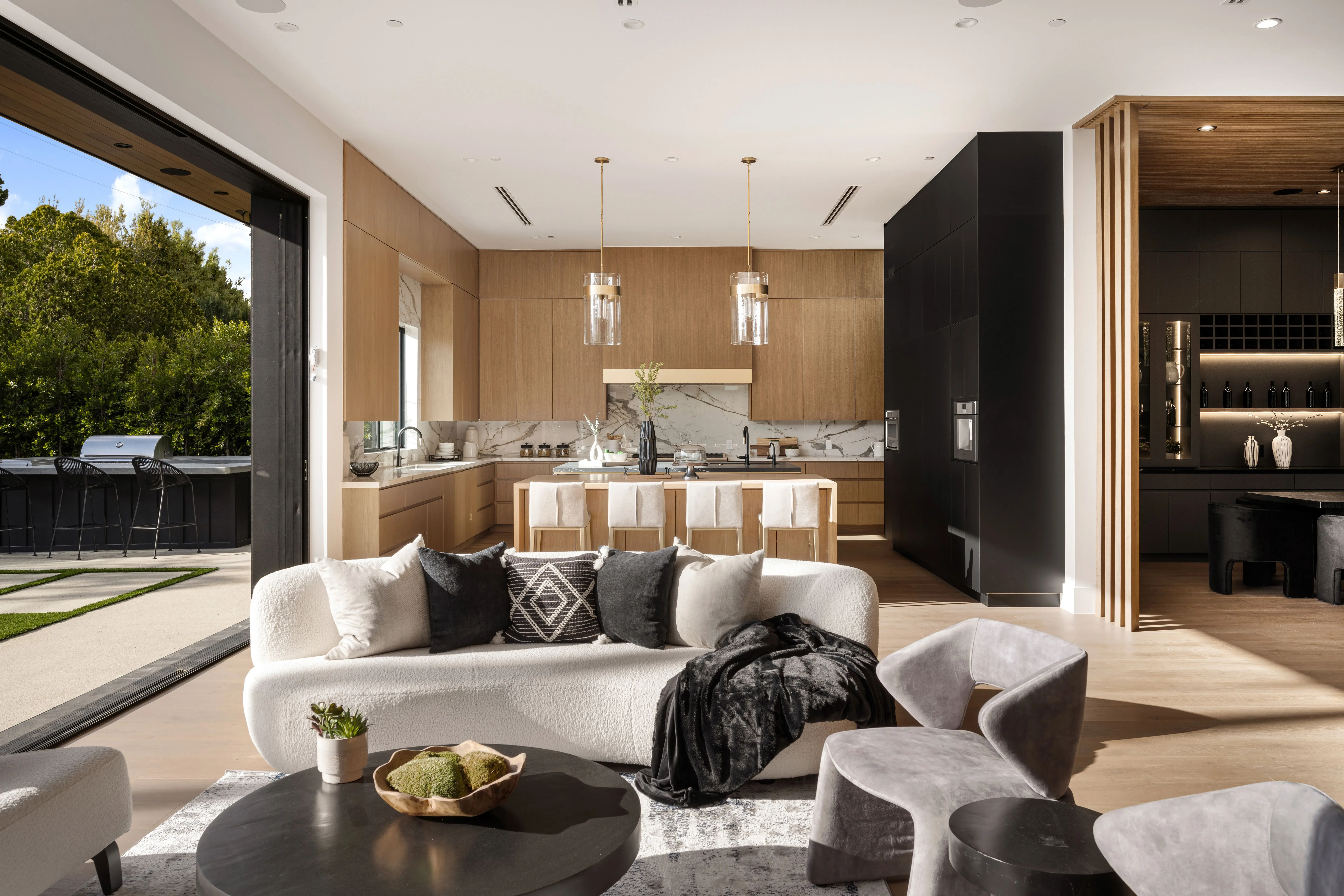 A modern open-concept living room and kitchen opening onto a garden patio