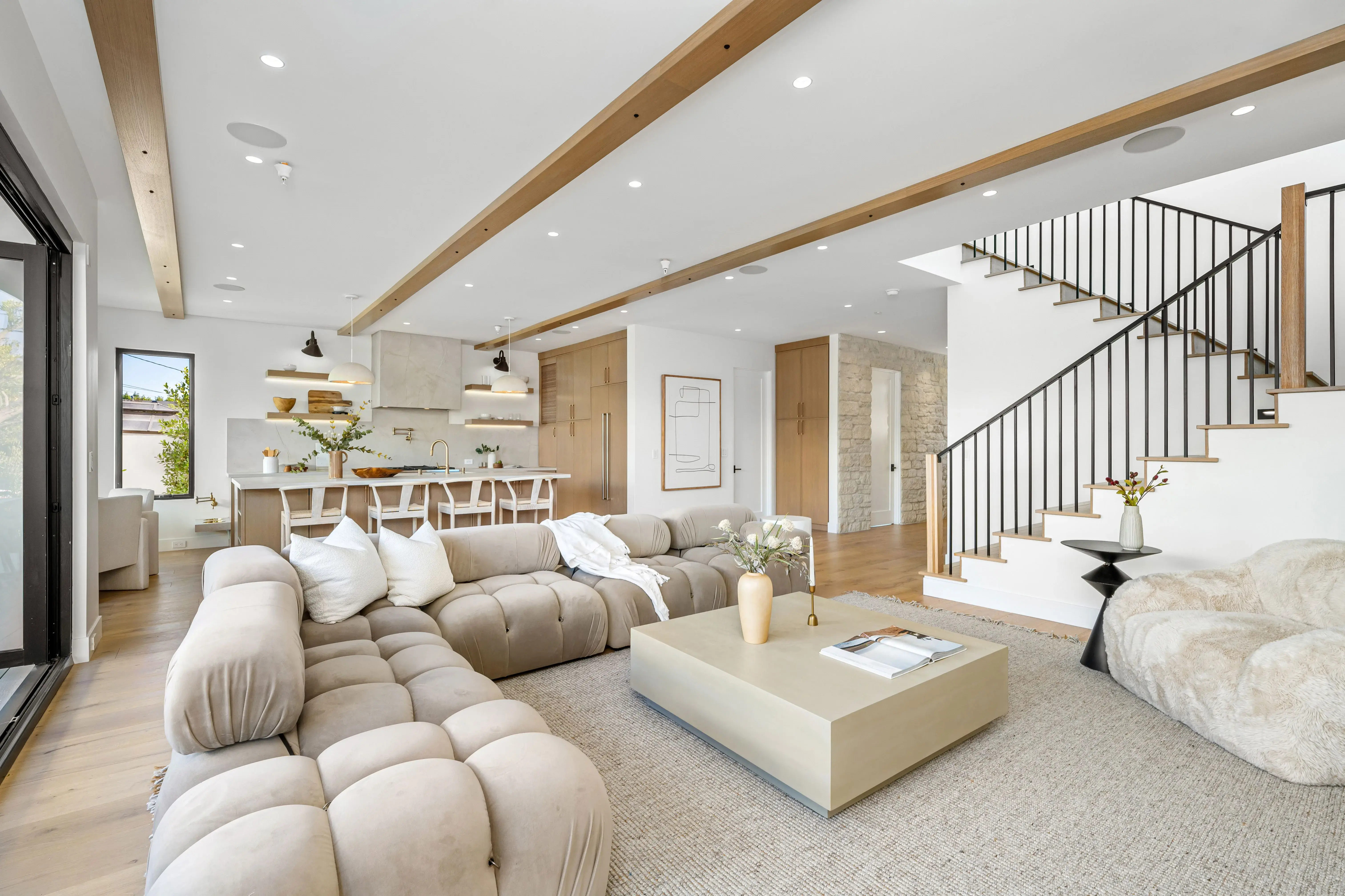 A bright, modern open-concept living room with a kitchen and staircase