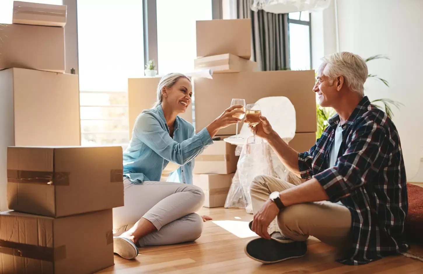 A couple toasting with wine among moving boxes in their new home